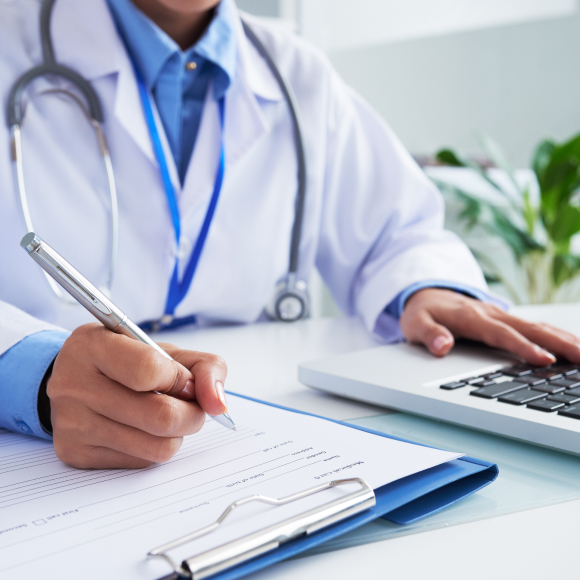 dottore in tavolo con computer e documenti da compilare